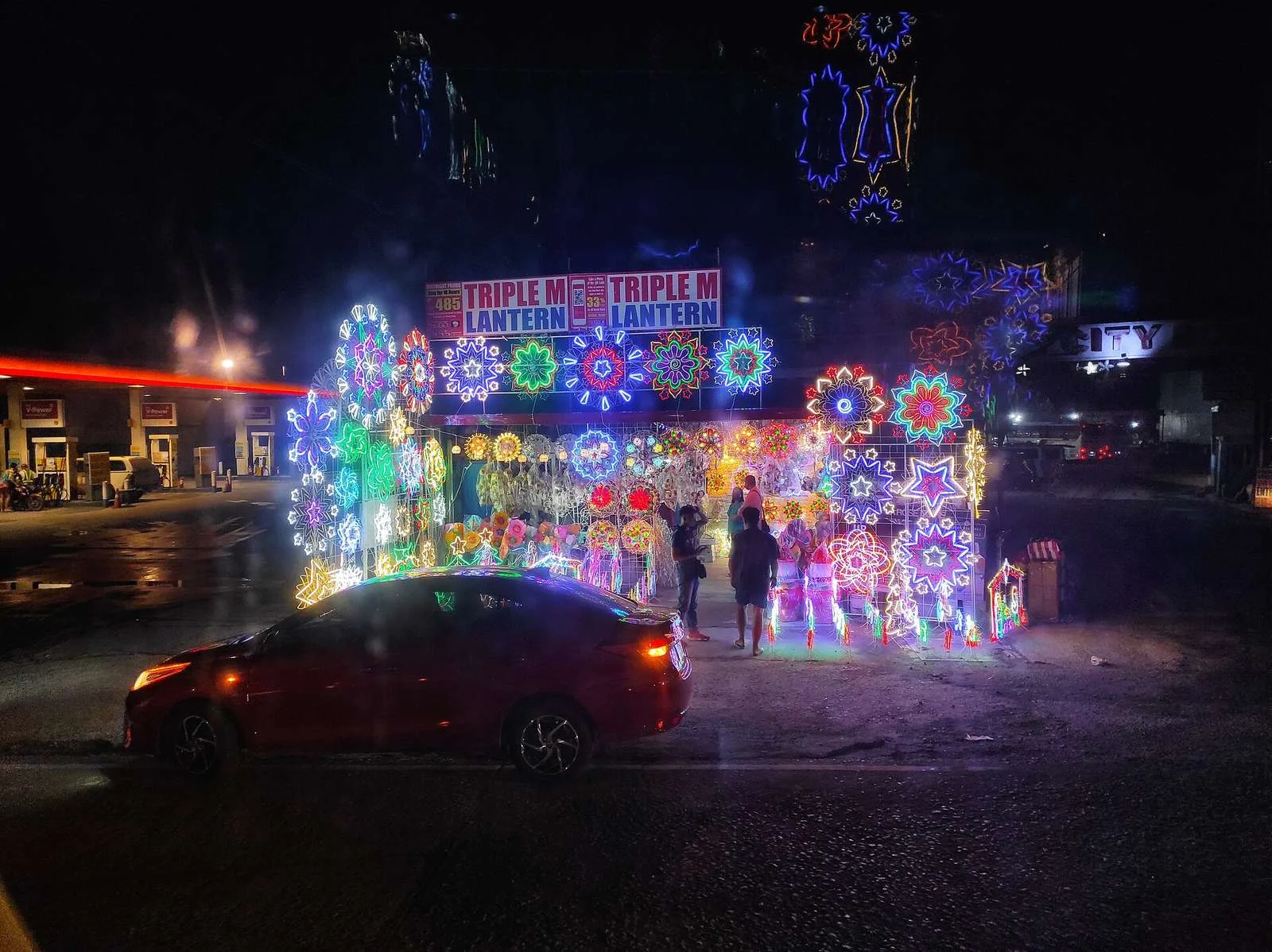 Roadside stall selling lit-up parol Christmas lanterns at night