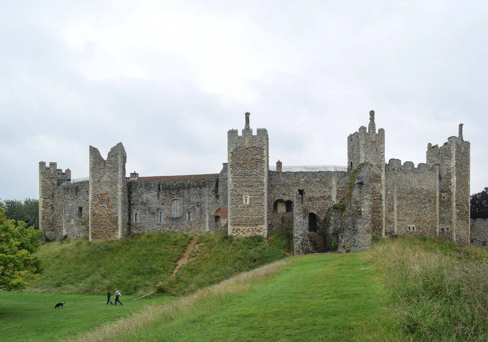 Curtain walls and towers of Framlingham Castle in Suffolk seen from the west across a grassy slope