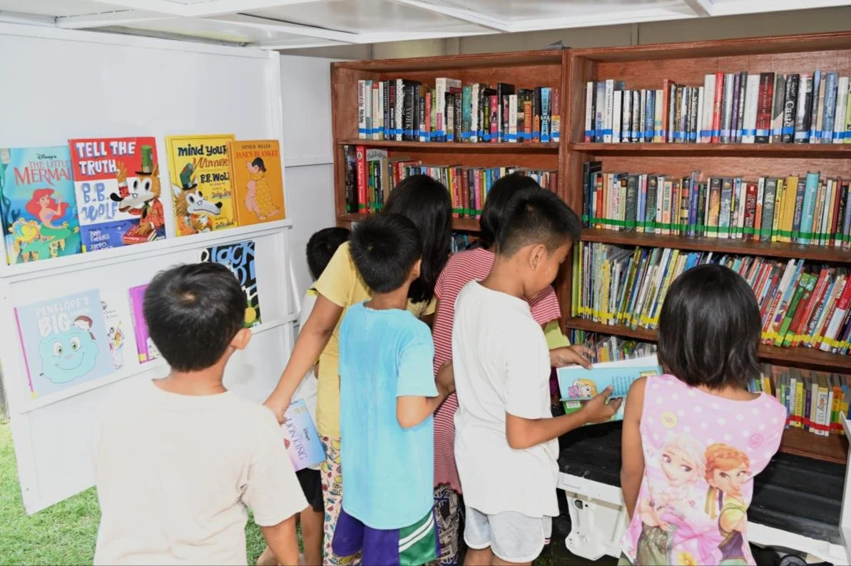 Children choosing books from the shelves of the Chapters of Change mobile library in Mindanao